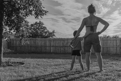 Rear view of man and woman standing on field
