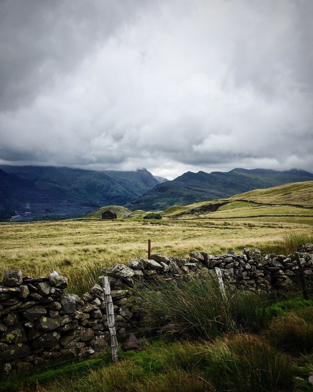 landscape, tranquil scene, tranquility, mountain, rural scene, solitude, scenics, farm, sky, cloudy, countryside, agriculture, remote, non-urban scene, field, cloud - sky, cloud, mountain range, beauty in nature, nature, outdoors, farmland, pile, green, day, cloudscape, horizon over land, dramatic landscape, stone