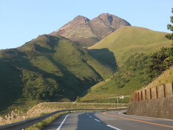 Road leading towards mountains against clear sky