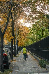 Rear view of man walking on footpath during autumn