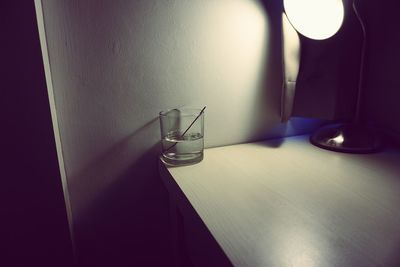 Close-up of electric lamp on table against wall