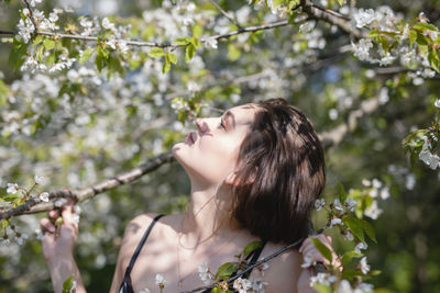Close-up of young woman by flowering tree