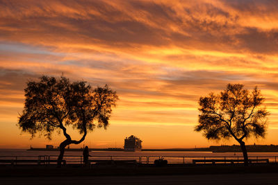 Silhouette trees by sea against orange sky in palma de mallorca