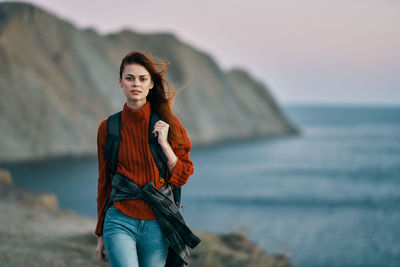 Portrait of young woman standing against sea