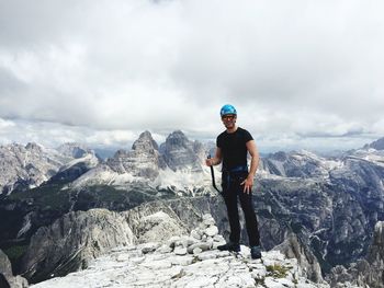 Portrait of man standing on rock against sky