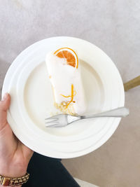 High angle view of hand holding plate with cake