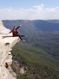 Woman sitting on mountain against sky