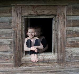 Portrait of smiling girl standing against wooden wall