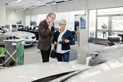 Senior couple discussing over car in store