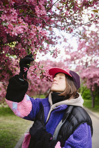 Woman wearing cap smelling apple blossoms in garden