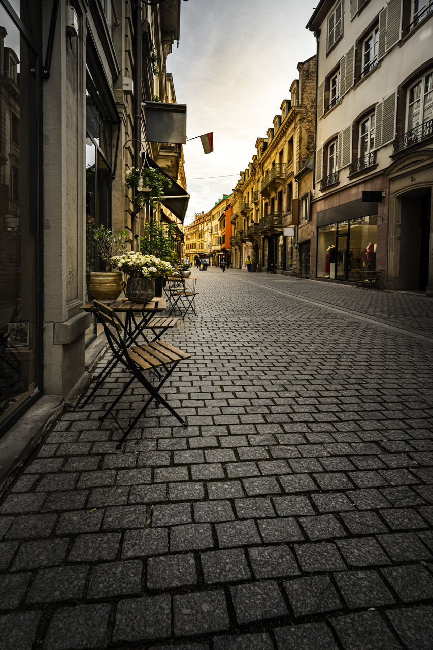 COBBLESTONE STREET AMIDST BUILDINGS AGAINST SKY