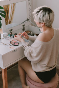 Midsection of woman sitting on table at home