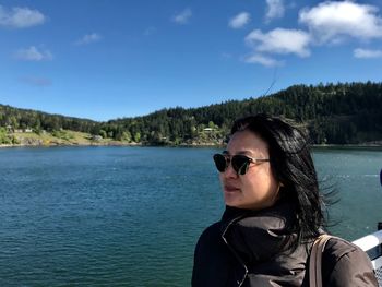 Woman wearing sunglasses against lake and sky