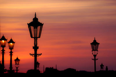 Silhouette street light against orange sky