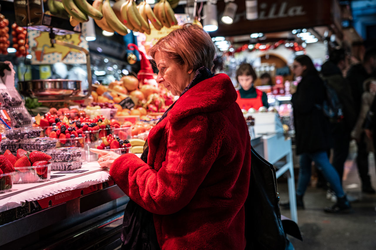 market, retail, real people, incidental people, women, food and drink, market stall, for sale, focus on foreground, adult, red, leisure activity, store, food, retail display, one person, lifestyles, choice, shopping, buying, consumerism, sale