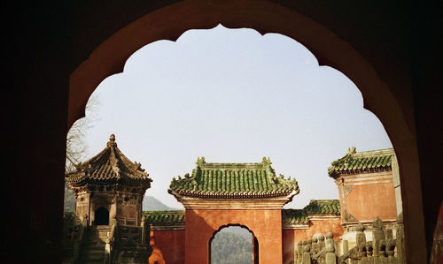 Low angle view of built structure seen through arch against clear sky