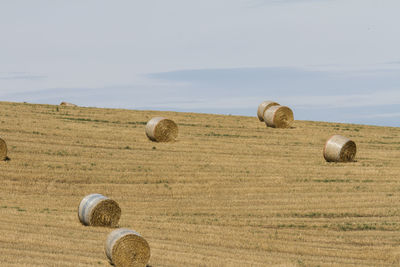 Hay bales on field against sky