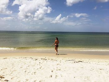 Rear view of woman at beach against sky