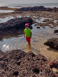 Boy standing on rock at beach