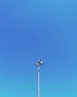 Low angle view of windmill against clear blue sky