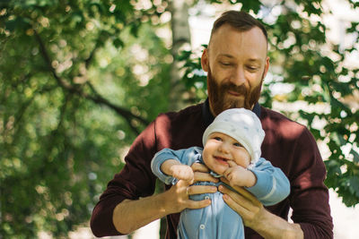 Portrait of father with daughter against trees