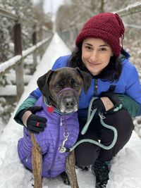 Portrait of woman with dog on snow covered bridge