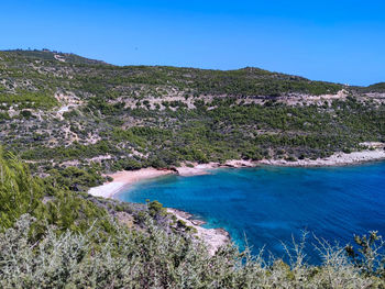 Scenic view of sea and mountains against clear blue sky