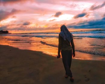 Full length of man standing on beach during sunset