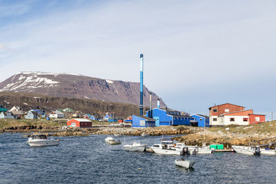 Sailboats in sea by buildings against sky