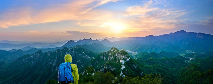 Hiker looking at mountains from great wall of china during sunset