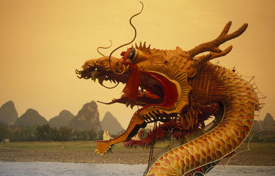 Chinese dragon by lake during sunset