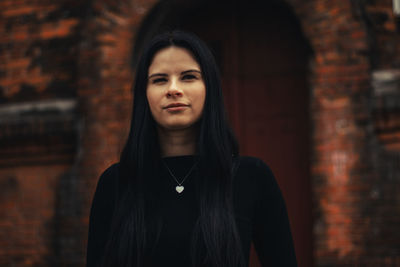 Portrait of beautiful young woman standing against wall