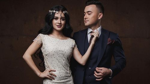 Portrait of young couple standing against wall