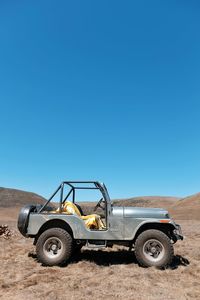 Tractor on field against clear blue sky