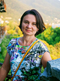 Adult woman close-up portrait on blurred foliage background