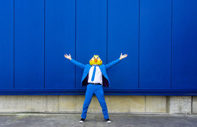 Full length of boy standing against blue wall