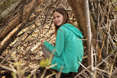 Young adolescent girl outside in lean-to tree fort treehouse tree house hangout she built