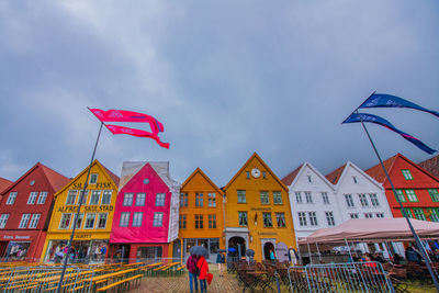 Multi colored flags against buildings in city against sky