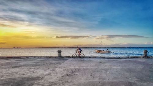 People on beach against sky during sunset