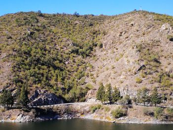 Scenic view of river by mountains against sky