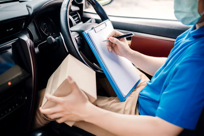 Midsection of woman holding smart phone in car