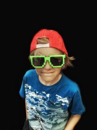 High angle view of boy wearing big green sunglasses against black background