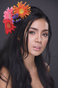 Close-up portrait of beautiful young woman against gray background