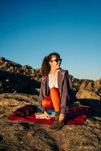 Young woman sitting on sunglasses against clear sky