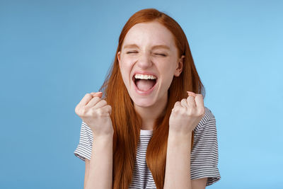 Portrait of young woman against blue background