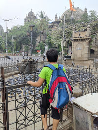 Rear view of boy standing by street watching pigeons 