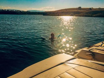 Shirtless man swimming in lake against sky