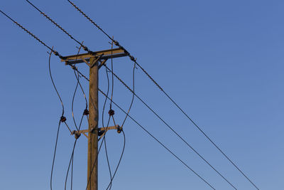 Low angle view of electricity pylon against clear sky