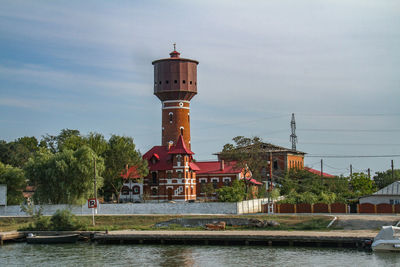 Built structure by river against sky