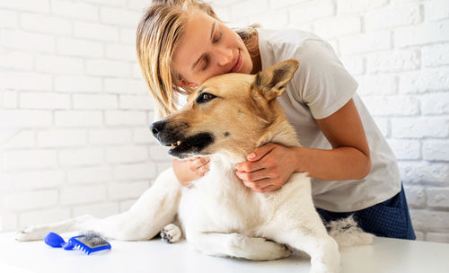 Portrait of woman with dog against wall